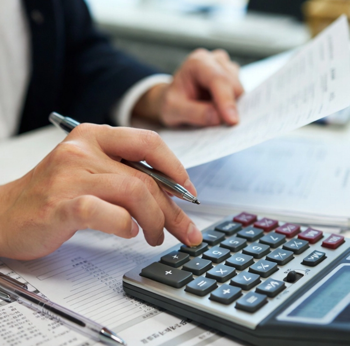 2026년 최저임금 실수령액 계산을 위해 계산기와 급여명세서를 함께 놓고 손으로 숫자를 계산하는 장면, 한국인 30대 직장인의 손, 사무실 책상 위, 자연광